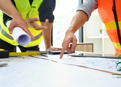 Two artisans in safety vests reviewing engineering blueprints and technical drawings, representing the hands-on skills of a Millwright