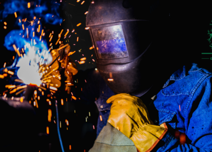 Boilermaker welding a steel plate wearing yellow protective gloves, Artisan Training Institute