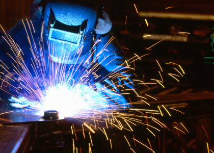 Boilermaker apprentice welding steel with bright arc sparks flying, Artisan Training Institute