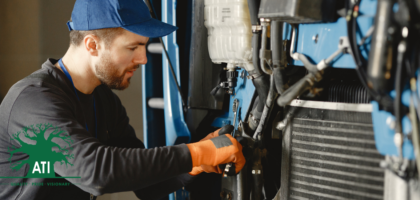Diesel mechanic using a wrench to service a truck engine radiator, Artisan Training Institute