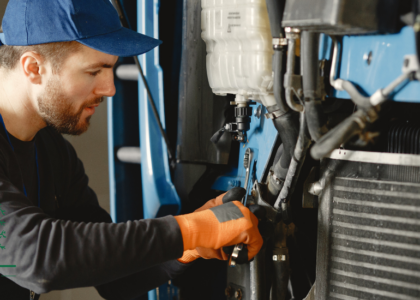 Diesel mechanic using a wrench to service a truck engine radiator, Artisan Training Institute