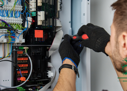 Electrician working inside an open control panel, connecting colour-coded wiring to terminal blocks, representing an Electrician career