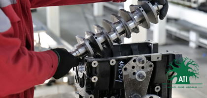 Artisan in a red work jacket fitting a crankshaft into an engine block in a workshop, representing Fitter and Turner training at Artisan Training Institute