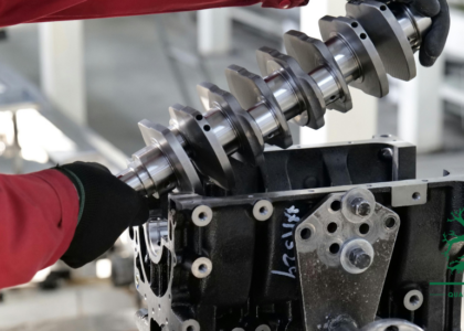 Artisan in a red work jacket fitting a crankshaft into an engine block in a workshop, representing Fitter and Turner training at Artisan Training Institute