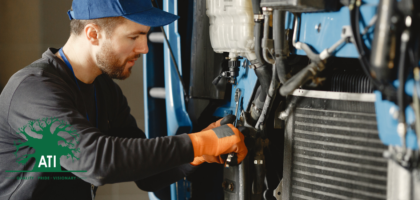 Heavy equipment mechanic in a cap and safety gloves using a spanner to service a machine engine, representing a Heavy Equipment Mechanic career