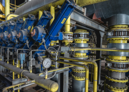 Row of blue hydraulic actuators and yellow pipework on an industrial pump station, representing mechanical fitter training at Artisan Training Institute