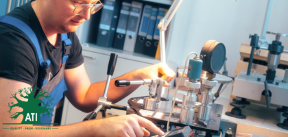 Mechanical fitter apprentice in safety glasses and overalls assembling a precision clamping fixture at a workbench, representing a mechanical fitter career